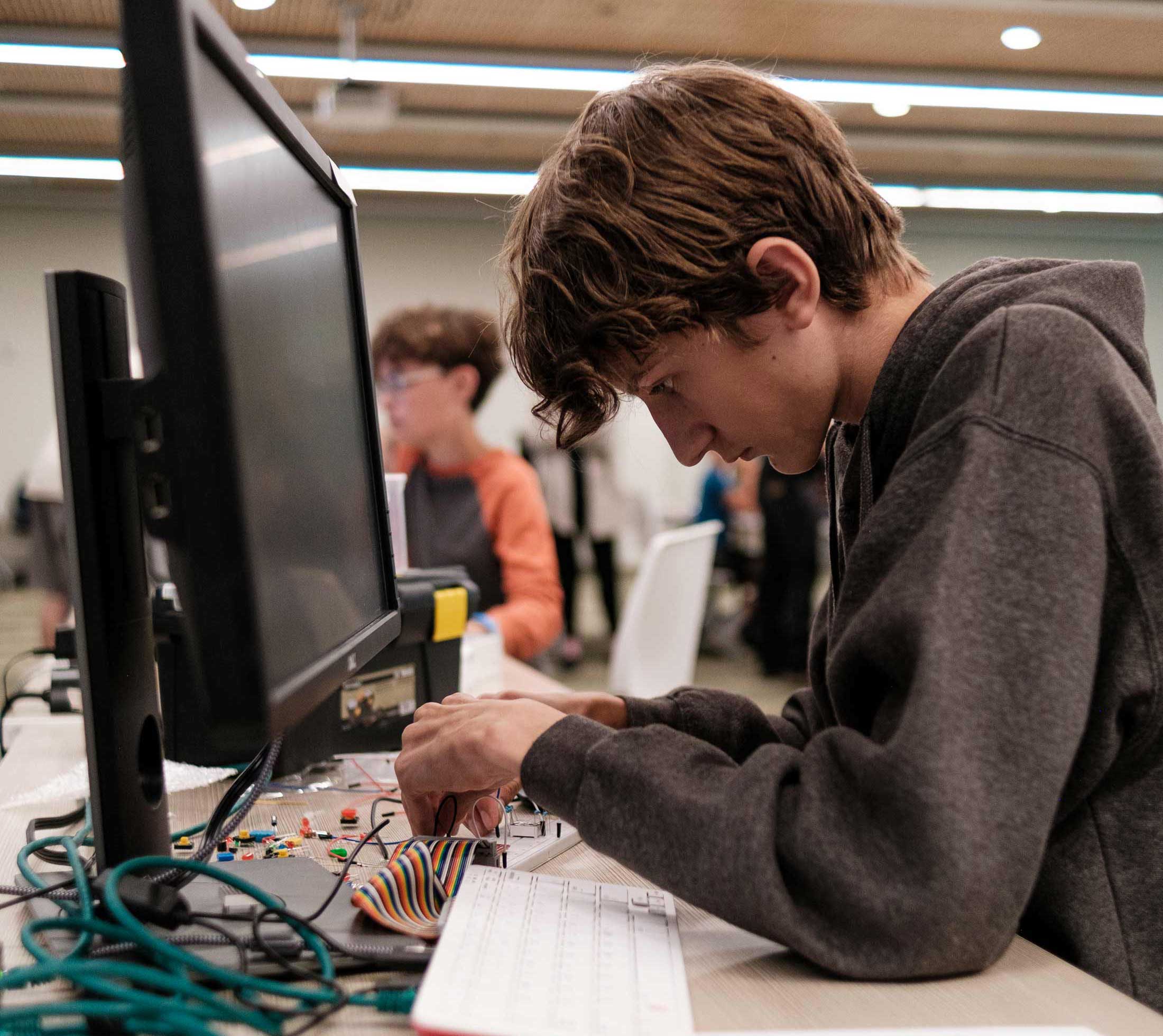 Kid working on a breadboard infront of a computer