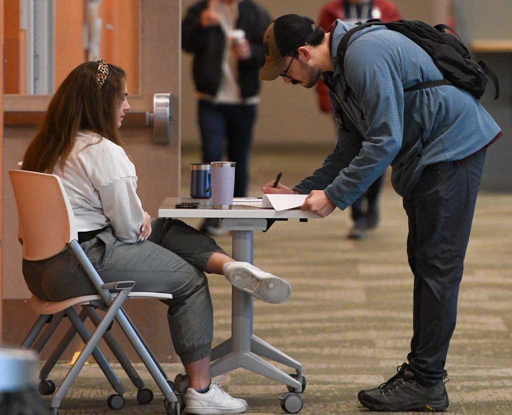 Man signing up for STEM camp at a table in a hallway
